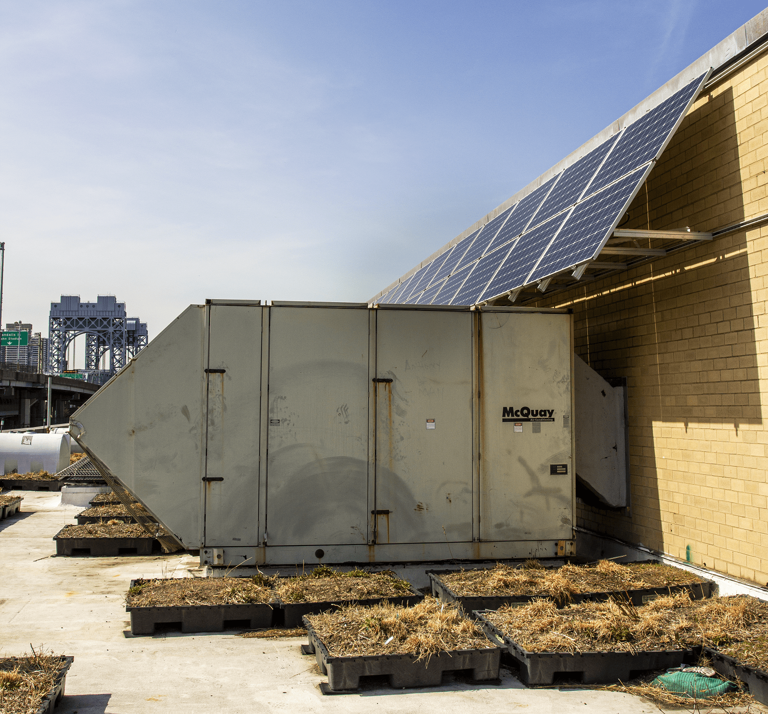 A picture of modular trays of green roof slotted around a large piece of machinery.